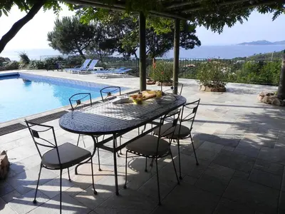 a table and chairs on a patio next to a pool at panopé in Porto-Vecchio