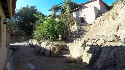 a stone wall next to a building with trees at Galate in Porto-Vecchio
