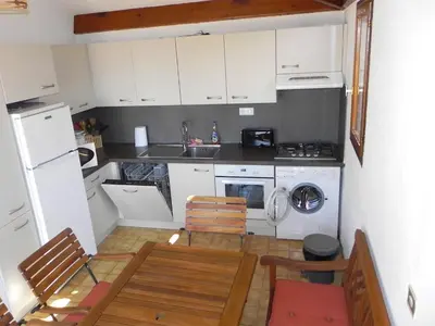 a small kitchen with white cabinets and a table and chairs at Galate in Porto-Vecchio