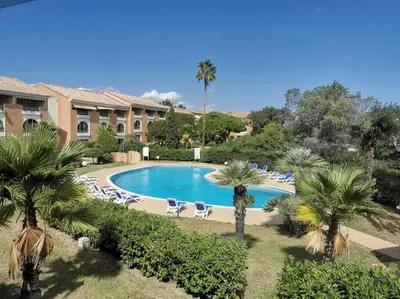 a pool with chairs and palm trees in a resort at Studio mezzanine 4 personnes Linguizetta marine de Bravone Corse in Linguizzetta