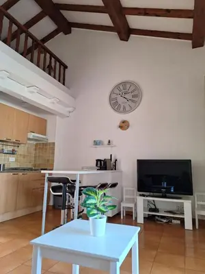 a room with a table and a clock on the wall at Studio mezzanine 4 personnes Linguizetta marine de Bravone Corse in Linguizzetta