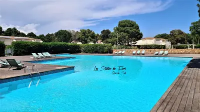 a swimming pool with chairs and a sign in the water at Les Studios de Fiori - Studios et Appartement T2 - Cala Rossa - proche Porto Vecchio in Lecci