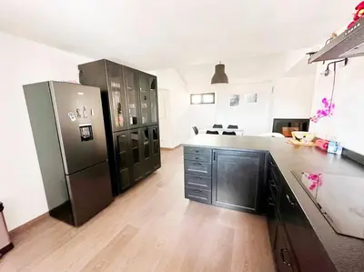 a large kitchen with a black refrigerator and wooden floors at Magnifique duplex de 130 m² à Corte (centre ville) in Corte