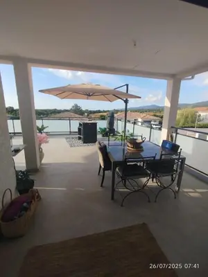 a patio with an umbrella and a table and chairs at VILLA entre mer, montagnes, étangs et rivières in Ventiseri