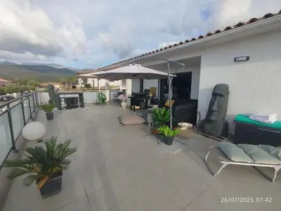 a patio with an umbrella and chairs on a balcony at VILLA entre mer, montagnes, étangs et rivières in Ventiseri