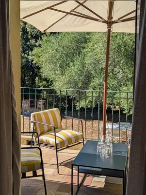a patio with a chair and a table and an umbrella at Magnifique villa entre mer et montagne in Calenzana