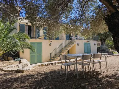 a table and chairs in front of a house at Magnifique villa entre mer et montagne in Calenzana