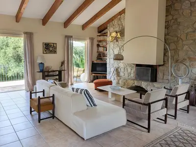 a living room with a white couch and a stone fireplace at Magnifique villa entre mer et montagne in Calenzana