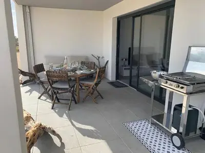 a kitchen and dining room with a table and a stove at Domaine d'Arca Eluard 02- PORTO-VECCHIO - Rez de jardin - 2 à 4 pers in Porto-Vecchio