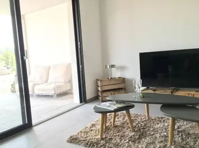 a living room with a table and a tv at Domaine d'Arca Eluard 02- PORTO-VECCHIO - Rez de jardin - 2 à 4 pers in Porto-Vecchio