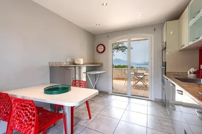 a kitchen with a table and red chairs and a table at L'Orangeraie - Maison avec vue pour 12 voyageurs in Grosseto-Prugna
