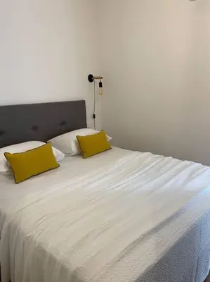 a white bed with two yellow pillows on it at Appartement centre ville Corte (F) in Corte