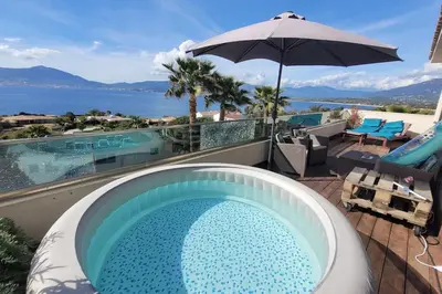 a swimming pool with an umbrella next to a swimming pool at Appartement terrasse et vue mer in Grosseto-Prugna
