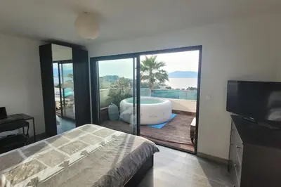 a bedroom with a tub and a balcony with a television at Appartement terrasse et vue mer in Grosseto-Prugna