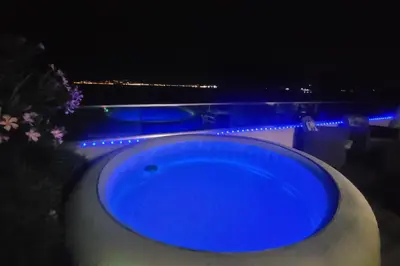 a blue tub sitting next to a pool at night at Appartement terrasse et vue mer in Grosseto-Prugna