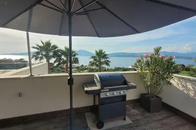a grill on a balcony with an umbrella at Appartement terrasse et vue mer in Grosseto-Prugna
