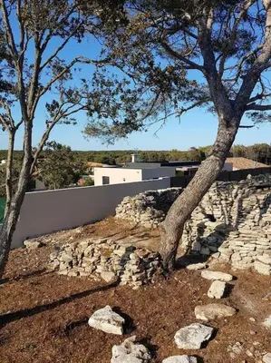 a stone wall and two trees in a yard at Villa neuve avec piscine in Bonifacio