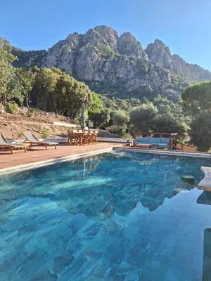 a swimming pool with a mountain in the background at Appartement Jardin et Piscine Les anges du maquis location Corse-du-Sud in Conca