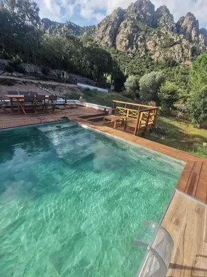 a swimming pool with mountains in the background at Appartement Jardin et Piscine Les anges du maquis location Corse-du-Sud in Conca