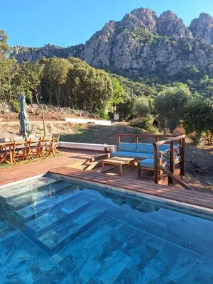a swimming pool with a bench and a picnic table at Appartement Jardin et Piscine Les anges du maquis location Corse-du-Sud in Conca
