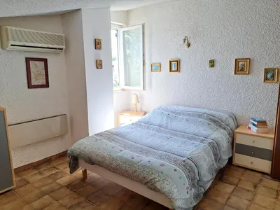 a bedroom with a bed and a window at Mini villa jardin 50 m plage in Borgo