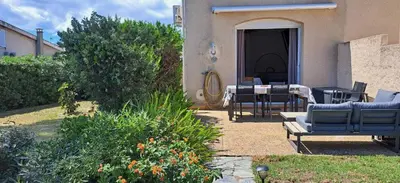 a patio with a table and chairs in front of a house at Mini villa jardin 50 m plage in Borgo