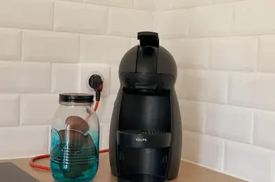 a coffee maker and a glass of water on a counter at Appartement les pieds dans l'eau in Solaro