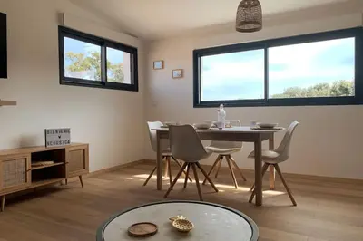 a dining room with a table and chairs and two windows at Appartement les pieds dans l'eau in Solaro