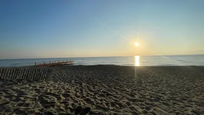 a beach with the sun rising over the ocean at Chez Céline & Rudi in Moriani Plage