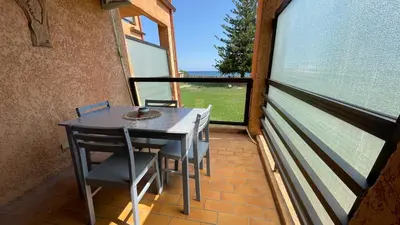 a table and chairs on a balcony with a large window at Chez Céline & Rudi in Moriani Plage