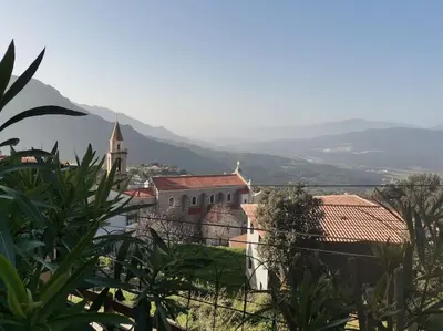 a building with a church and a mountain in the background at Entre Mer et Montagne in Sartène