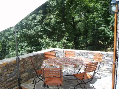a table and chairs on a patio with a stone wall at HAUTE CORSE CENTRE CORSE CASTAGNICCIA Gîte de PETRERA 1 CASABIANCA in Casabianca