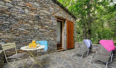 a patio with chairs and a table and a stone building at HAUTE CORSE CENTRE CORSE CASTAGNICCIA Gîte de PETRERA 1 CASABIANCA in Casabianca