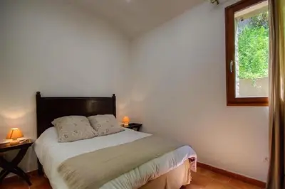 a bedroom with a bed with two tables and a window at HAUTE CORSE CENTRE CORSE CASTAGNICCIA Gîte de PETRERA 1 CASABIANCA in Casabianca