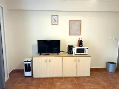 a television on a cabinet with a microwave on it at Appartement, 60m2, 6 couchages avec piscines à Marine de Bravone, Linguizetta, résidence Sognu Di mare Corse in Linguizzetta