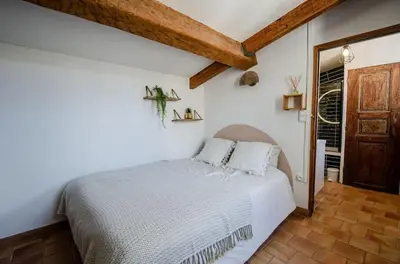 a bedroom with a white bed and a wooden door at Charmant T2 au Cœur d'Ajaccio - Parking & AC in Ajaccio