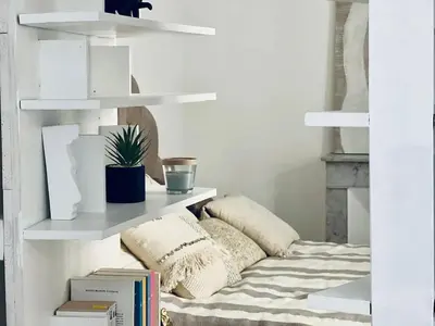 a white shelf with pillows and books on a bed at Casamea - Apt Spacieux, Clim, Famille & Cabane in Ajaccio
