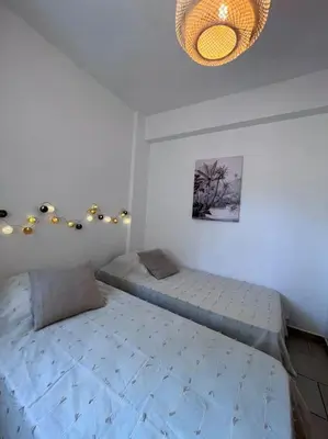 a bedroom with two twin beds and a chandelier at Appartement rénové tout confort 10mn de Campomoro in Grossa