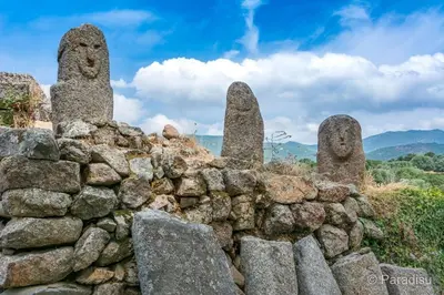 a stone wall with three large stone statues at Appartement rénové tout confort 10mn de Campomoro in Grossa