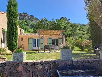 a house with a stone wall in front of a yard at Villa Cutalello coté montagne Calenzana in Calenzana
