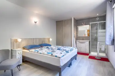 a bedroom with a large bed and a chair at Villa Cutalello coté montagne Calenzana in Calenzana