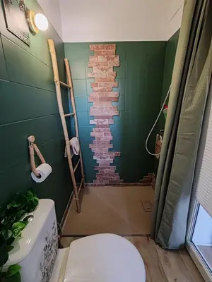 a bathroom with a toilet and a brick wall at Casa Davia. Studio indépendant meublé. in Furiani