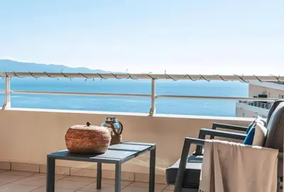 a table and chairs on a balcony with a view of the ocean at CAPO FENO AJACCIO in Ajaccio