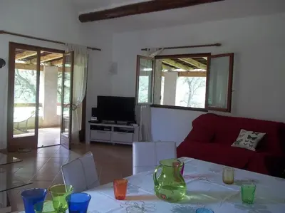 a living room with a table and a red couch at QUIET COTTAGE NEAR CITY CENTER in Porto-Vecchio