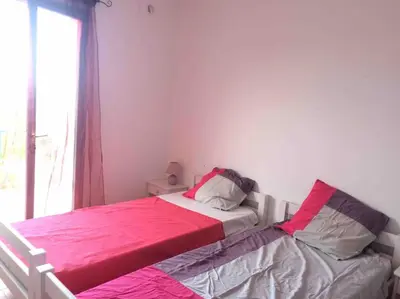 a bedroom with a bed with pink sheets and a window at Fraîcheur et calme en montagne 30 mn de la mer in Porto-Vecchio