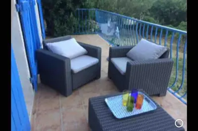 a patio with two chairs and a table with a drink at Fraîcheur et calme en montagne 30 mn de la mer in Porto-Vecchio