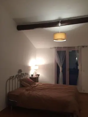 a bedroom with a bed and a lamp and a window at Fraîcheur & calme en Montagne, 30minutes de la mer in Porto-Vecchio