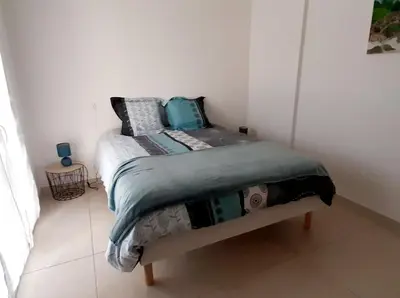 a bed in a white room with a bedskirtspectspectspects at Bel appartement Corse côte Est in Morta