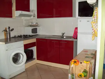 a kitchen with red cabinets and a washing machine at La Corse mer turquoise et sable fin in Poggio-Mezzana