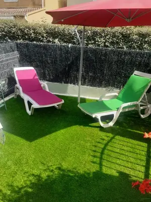 two lawn chairs and an umbrella on the grass at La Corse mer turquoise et sable fin in Poggio-Mezzana